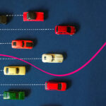 Many cars travel on straight lines while a pink one veers of the path