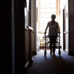 Silhouette of a senior woman using a walker in the hallway of a retirement home