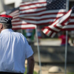 a veteran stands in front of several American flags