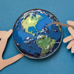 Conceptual paper illustration of human hands and the Earth in a lab.