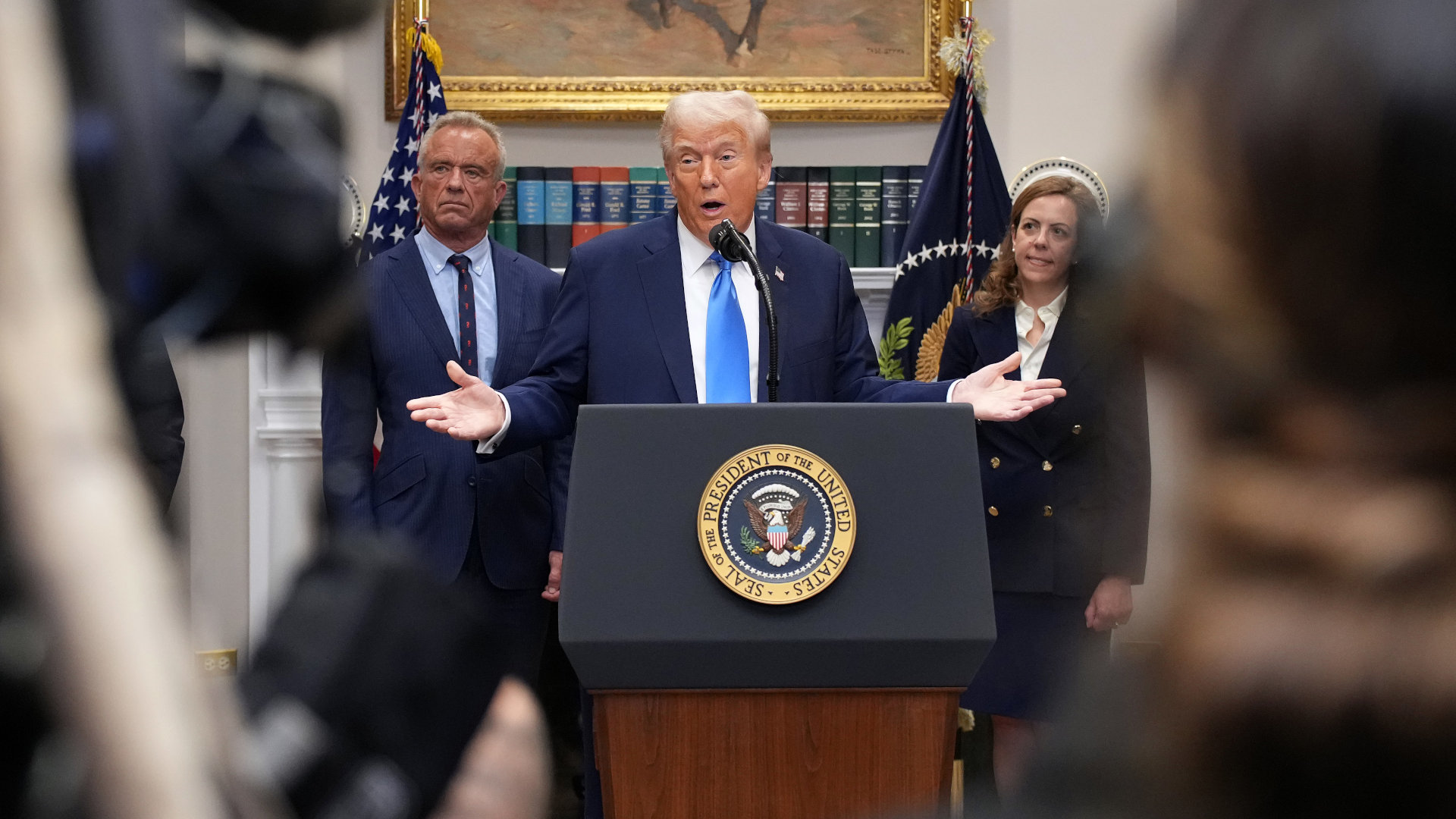 president trump standing at a podium with his arms out