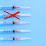 Disposable syringes on a blue background. Red "X" through one