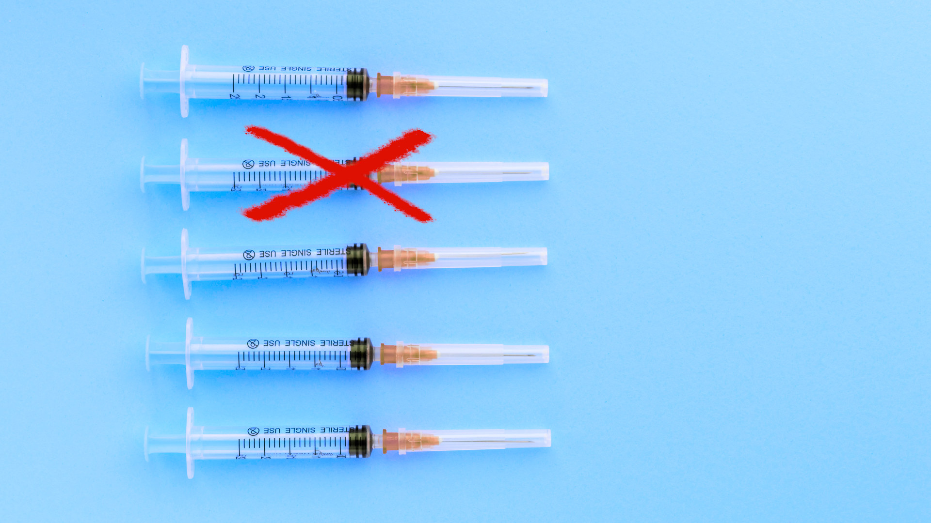 Disposable syringes on a blue background. Red "X" through one