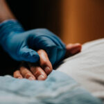 Medical staff wearing surgical glove holding hand of patient at clinic
