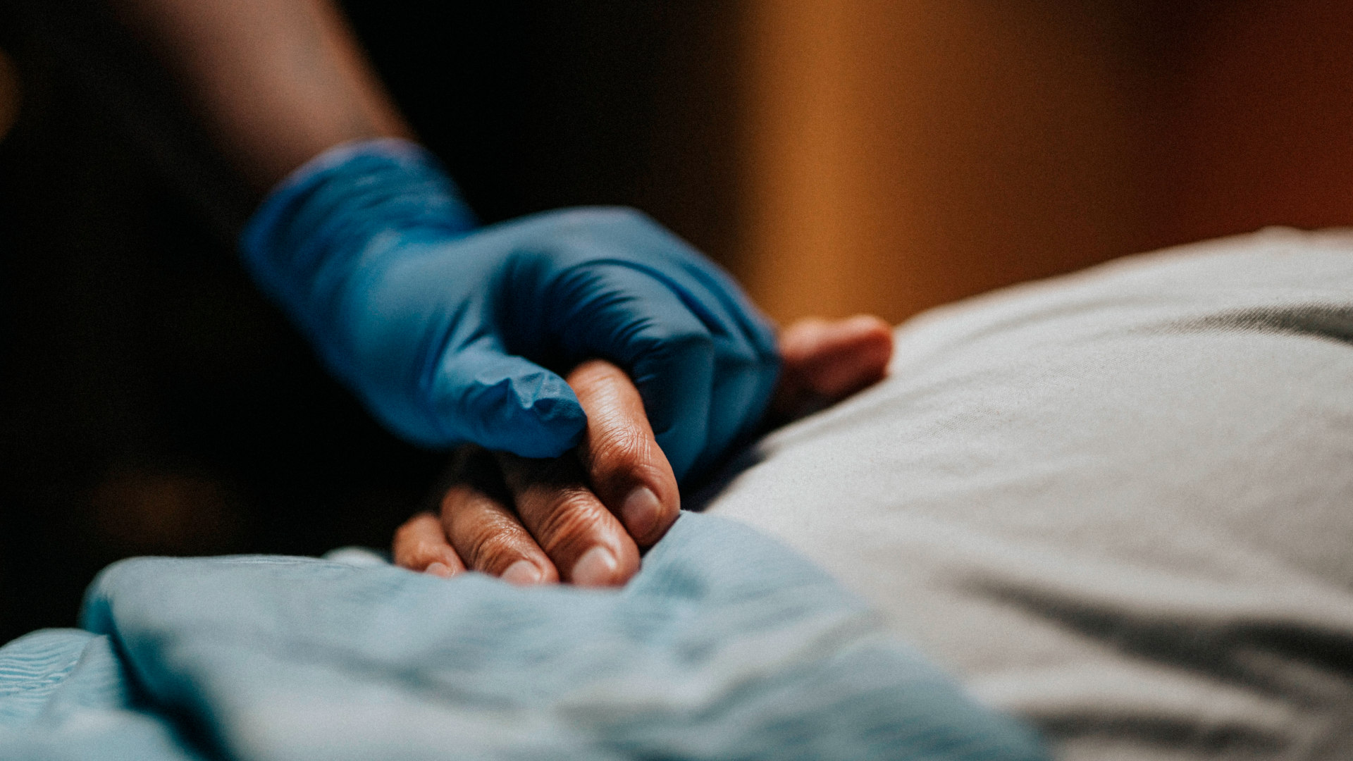 Medical staff wearing surgical glove holding hand of patient at clinic