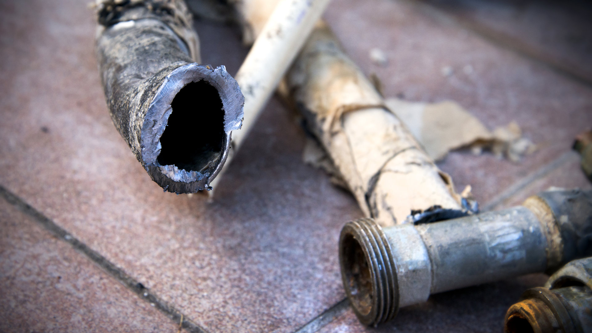 Close-up of a discarded lead pipes on tiled floor