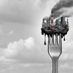 A fork with industrial toxins stacked upon it sits against a cloudy background
