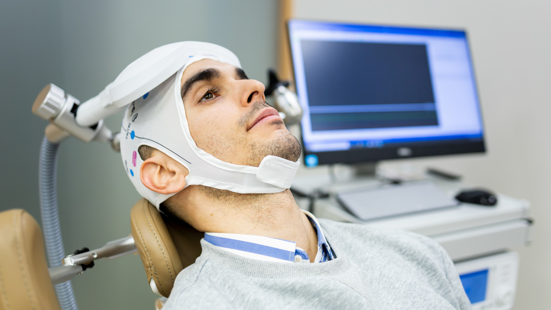 A man in his 30s or 40s undergoes transcranial magnetic stimulation therapy in a psychiatric clinic.