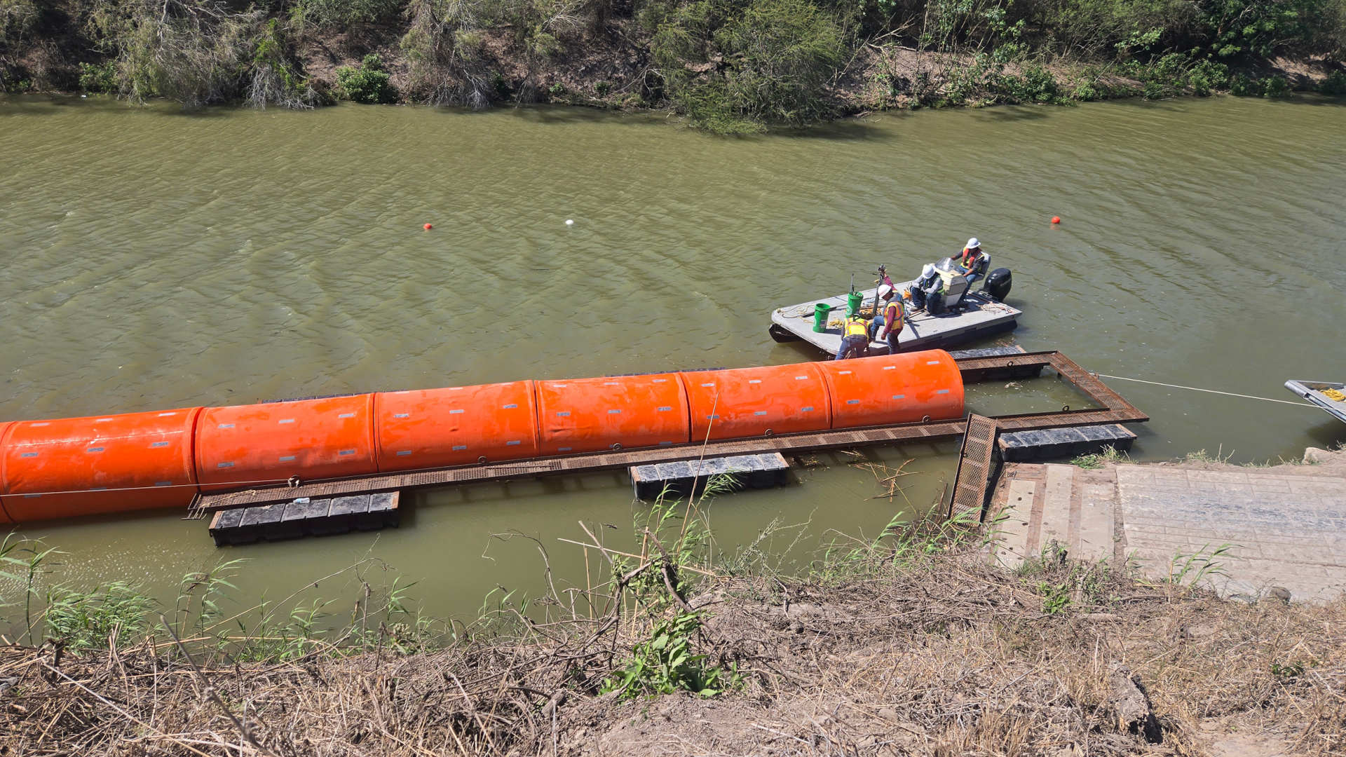 large orange buoys float in a murky river