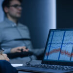Computer Shows Physiological Measures of a Man Undergoing Lie Detector / Polygraph Test. Examining Expert Writes Down Observations.