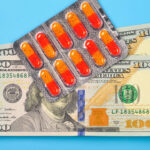 Blister pack of red and orange pills, and money on a blue background.