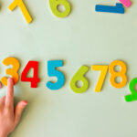 a child's hand points to multi colored numbers