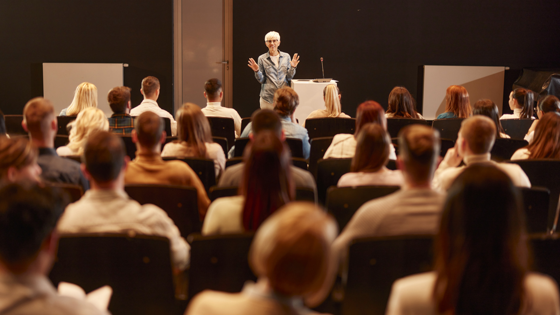 Animated public speaker talking on a conference at convention center.